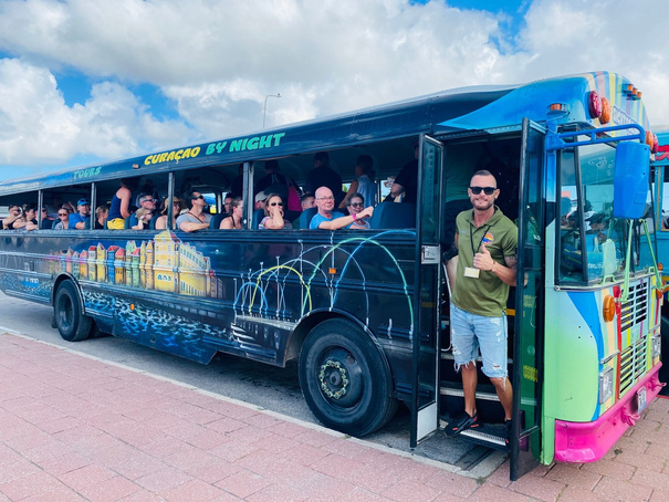 Guide von Next Level Travel öffnet die Tür des farbenfrohen CuraVida-Schulbusses
